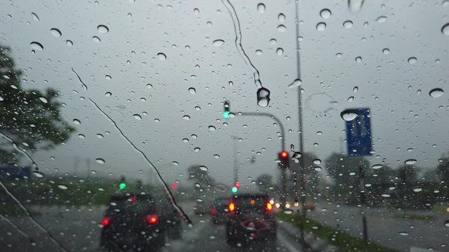 Rain drop falling on car windshield, drive car on street in city at heavy rain