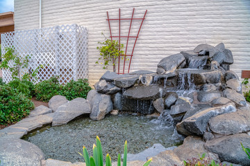 Artificial stone cascade waterfall in backyard on a sunny day