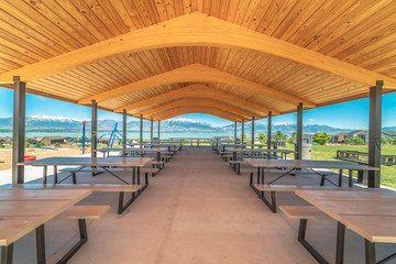 Fototapeta na wymiar Pavilion with brown wooden ceiling overlooking lake and snow capped mountain