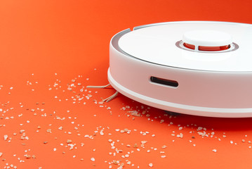 Robot vacuum cleaner in the job removes debris fart by itself. Robot vacuum cleaner isolated on red background. close up photo