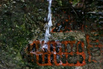 blurred stream of spring water falling on the base of the brick