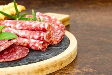 Meat and cheese plate antipasti snack with Prosciutto ham, Parmesan, Blue cheese, Cantaloupe melon and Olives on olive wood serving board on dark stone background