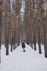 Portrait of a girl in a warm gray coat and burgundy knit scarf in the winter woods.