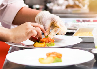 Obraz na płótnie Canvas Chef cooking, Chef preparing food in the kitchen, Chef decorating dish, closeup.