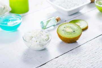 beauty products with kiwi fruit ingredient on white wooden table