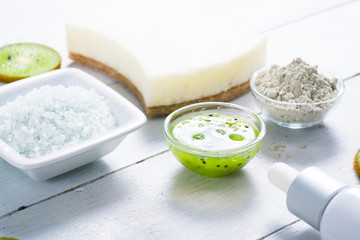 beauty products with kiwi fruit ingredient on white wooden table