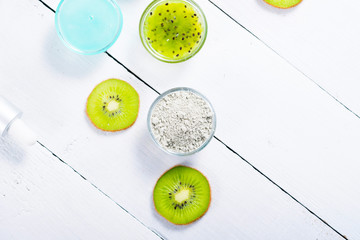 beauty products with kiwi fruit ingredient on white wooden table