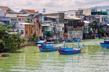 Bright fishing boats in the bay, Vietnam. blue boats with red details. Traditional Vietnamese buildings in the background