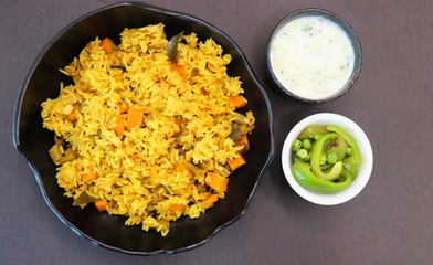 ndian Vegetable Pulav or Biryani made using Rice and vegetables like peas, carrots, beans. served with raita and saute peas, capsicum bowl.