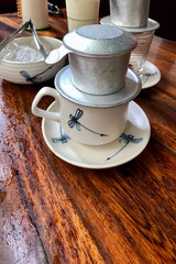 coffee dripping in vietnamese style. Ceramic mugs with a dragonfly pattern on a wooden table. authentic vietnamese cafe