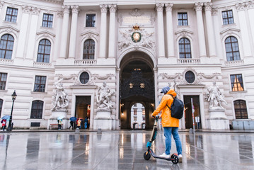 man in yellow raincoat riding by city street at electric scooter © phpetrunina14
