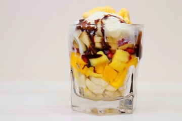 Mango & vanilla ice cream served with Mixed chopped fruits like Bananas, Mangoes, pomegranates, apples garnished with chocolate syrup in a glass. known as Gad bad ice cream in India © Manaswi