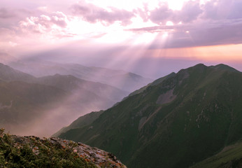 Rays of the sun through the clouds in the mountains at sunset time