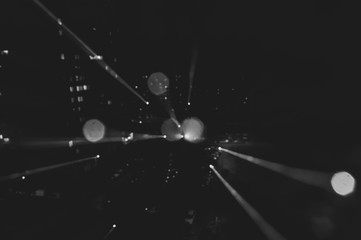 Blurry glare of the night city. Background for a dynamic picture. Black and white frame.