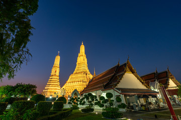 Fototapeta premium Large illuminated temple Wat Arun after sunset seen accross river Chao Phraya Bangkok, Thailand.golden Buddha in side temple Wat Arun the biggest and tallest pagoda in the world