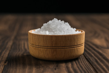Salt in a wooden saltshaker on a dark rustic table.