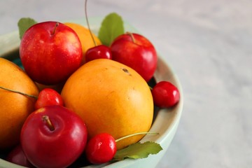 Bowl of mixed or assorted fruits and berries on the table, Raw mangoes, Mangoes, Red cherries and Fresh Plums. Moody photography, dark background