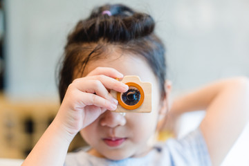 Little asian girl holding Wooden toy camera and take picture.Concept for photography, Photo Education.Kid talent and eye care.