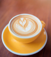 Coffee latte art in coffee shop on wooden table in the morning.