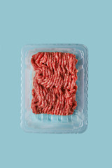 Ground beef or cultured artificial meat isolated on laboratory blue background. Plant based and clean protein concept. Future food trend of biotechnology 