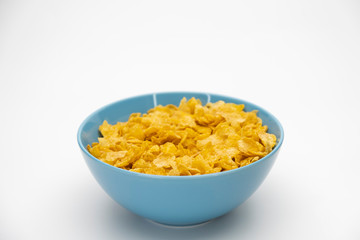 Golden cornflakes in the blue bowl isolated on white background