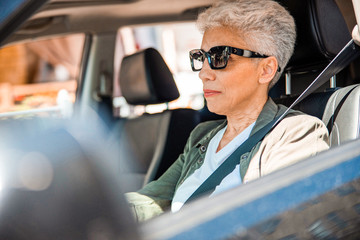 Elderly lady in sunglasses sitting in auto
