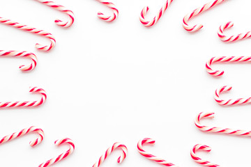 Christmas candies frame - cane with red and white stripes - on white background top-down copy space