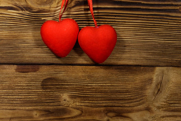 Two red hearts hanging over wooden background