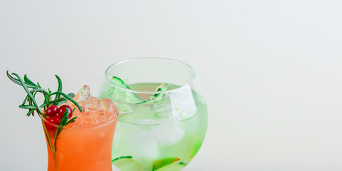 Two unique designed cups of cocktail drink with fruits and berries and ice on a wooden table. Copy space, banner