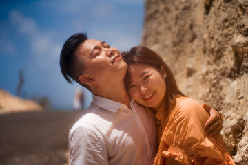 young happy and beautiful Asian Korean couple in love enjoying outdoors romantic journey playing sweet in cliff rock road exploring together in holidays travel adventure and wanderlust