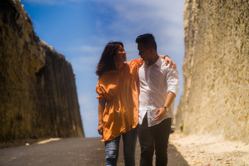 young happy and beautiful Asian Korean couple in love enjoying outdoors romantic journey walking in cliff rock road exploring the landscape together in holidays travel adventure