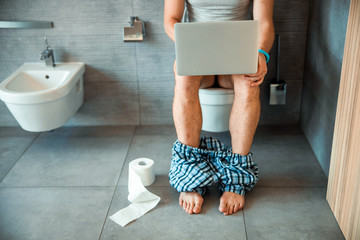 Young man working on laptop in restroom