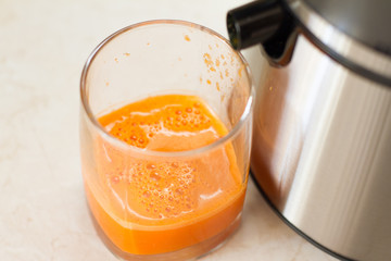 the process of making juice in the home kitchen. Healthy detox, vegetarian diet. A glass of fresh carrot juice. vegetables smoothies, healthy juicy vitamin drink diet. refreshing fruit drink