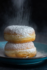 Pfannkuchen (Berliner) wird mit Puderzucker bestreut