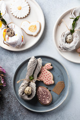 Table setting for the holiday of Easter. The photo shows white dishes, serving mat, Easter egg in a napkin. Napkin draped under rabbit ears.