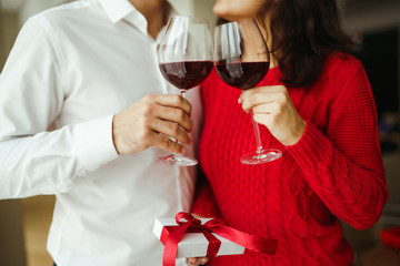 Hands holding glasses of wine on restaurant background. Couple clink glasses with red wine. Romance at restaurant for Valentine's Day- concept. Relationship & Birthday concept.