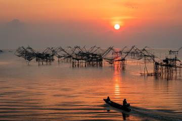 Landmark of traditional fishing net gears in the lake with beautiful sunrise scene and fisherman boat at Pakpra.
