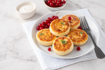 Syrniki or cottage cheese pancakes with fresh red currant. Tasty healthy breakfast.