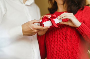 Valentine's Day, holiday and surprise concept. Man gives to his woman a gift box with red ribbon. A...