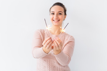 Holidays and festive concept - Pleasant young woman holding sparklers on white background