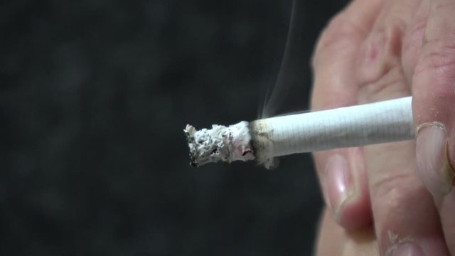 eine qualmende Zigarette wird in der Hand gehalten