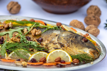 carp with lemon, walnuts and raisins on the plate