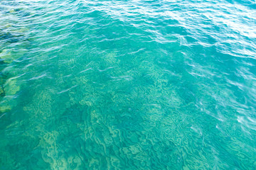 Clear water texture in blue. Background of the ocean and the sea backlit by the sun.