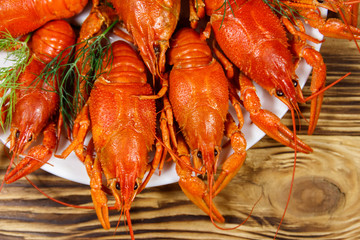 Boiled crayfish in plate on wooden table. Top view