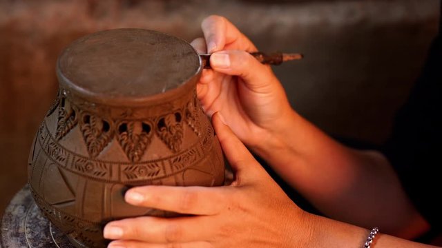 Hands make potter inflicts a decorative pattern on earthenware