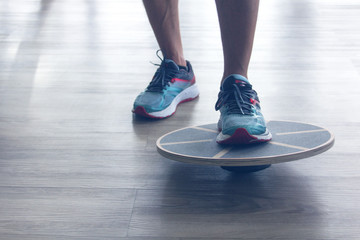 Mans legs in trainers testes balance board with one leg. 