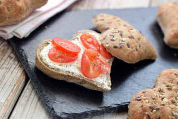 Whole grain bread in heart shape with tomatoes