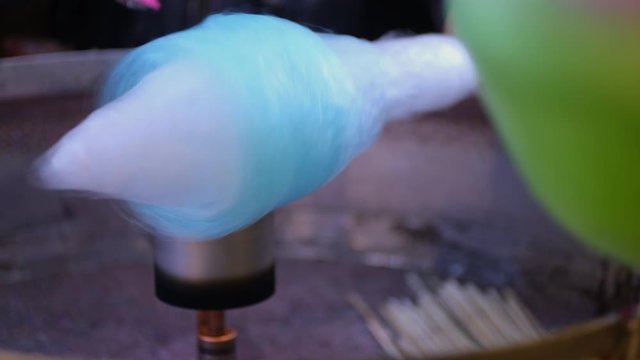 Making of cotton candy on festival. Street food. Night shot. Dessert