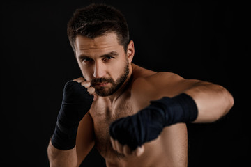 boxer man with bandage on hands training before fight and showing the different movements on black background