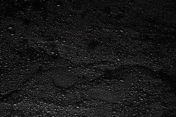 Dark gray black slate background with water drops or natural stone texture. Black board for serving close-up. Drops of water close-up on a black background